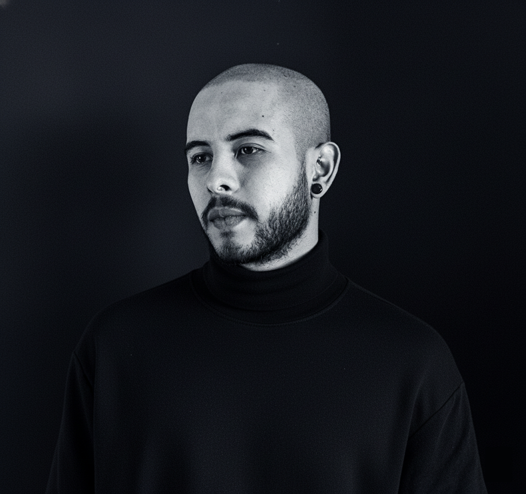Portrait of a man with brown hair and glasses on a flat gray background.
